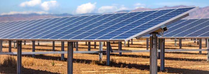 Looking up the intricate geometric structure of a tall powerline tower, framed against a soft pink sky.